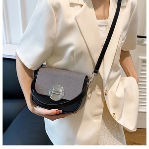 Detail of crossbody box bag featuring black leather, woven flap, and silver metal lock