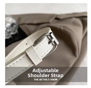Detail of adjustable white leather strap with polished silver buckle on a handbag