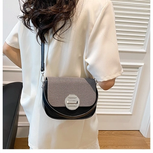 Detail of crossbody saddle bag with gray fabric stitching and metal lock on model