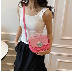 Detailed view of pink crossbody bag with corduroy texture and silver round metal buckle