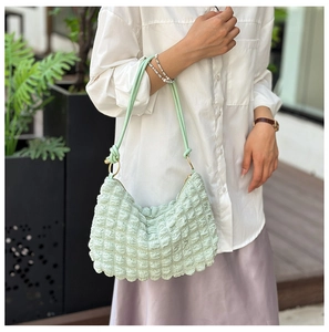 Detail of light green bubble texture fabric and silver rings on a shoulder bag