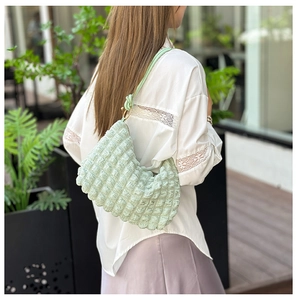 Detail of light green pleated shoulder bag with gold metal rings and bubble texture