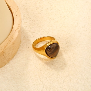 Detail of heart-shaped tiger eye stone set in a vintage style wide golden ring band