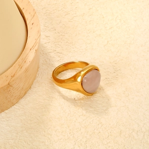 Macro detail of polished gold ring featuring a smooth translucent pink cabochon stone