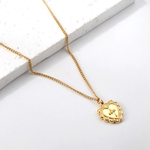 Vue détaillée du collier pendentif cœur doré en acier inoxydable avec motif croix