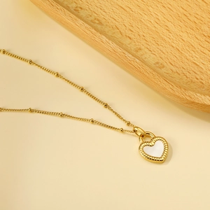 Gros plan du pendentif cœur doré avec insert blanc et bordure texturée en corde