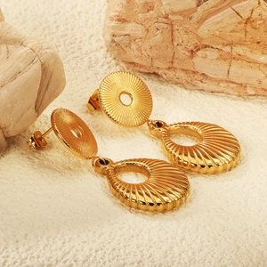 Detail showing irregular gold drop earrings with textured circular studs and shell patterns