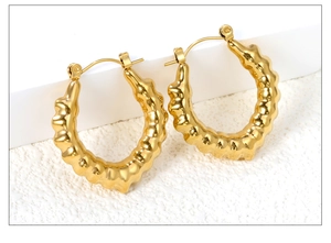Detailaufnahme der klobigen goldenen Creolen mit gewellter Metalloberfläche im Vintage-Stil