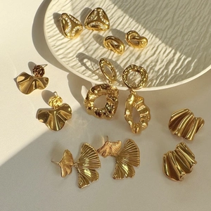 Textured gold irregular earrings set in a minimalist ceramic dish for a luxury style