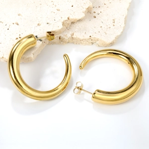 Detail of chunky gold hoop earrings on stone display showing 18K gold finish