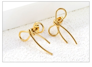 Macro detail of elegant golden bow stud earrings with a minimalist wire-wrapped design