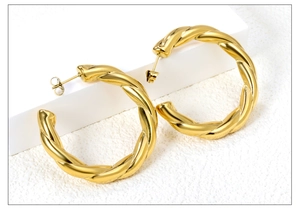 Macro view of gold twisted texture hoop earrings with detailed spiral metal finish