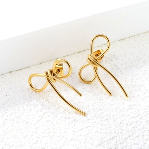 Elegant gold bow earrings with fringe tassels on minimalist display, stainless steel set