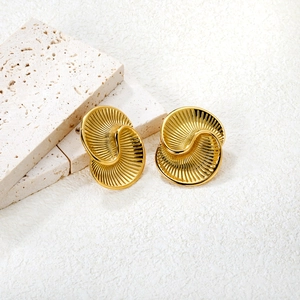 Golden geometric spiral earrings with textured swirl design on a minimalist background