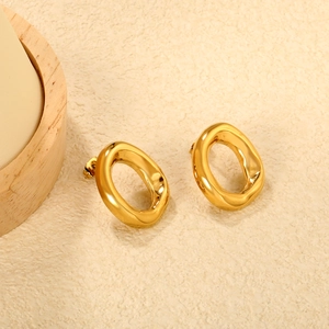 Macro shot of irregular oval golden earrings with polished mirror finish on a textured base
