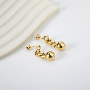 Detail of gold drop earrings featuring a thick chain link and polished solid metal ball