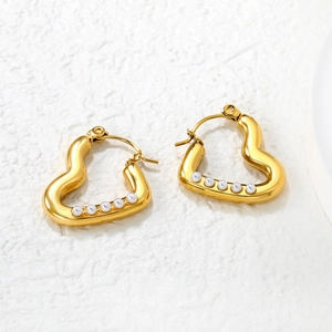 Boucles d'oreilles cœur dorées 18 carats avec perles blanches sur surface en pierre