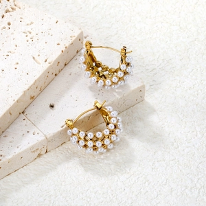 Détail de boucles d'oreilles créoles dorées 18K ornées de trois rangées de perles sur pierre