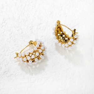 Détail de boucles d'oreilles en C plaquées or 18K avec trois rangées de perles d'imitation