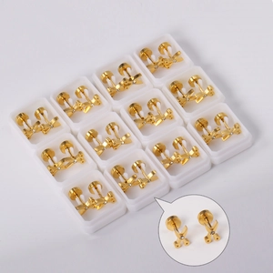 Macro detail of 12-piece set of golden scissors-shaped earrings with rhinestones