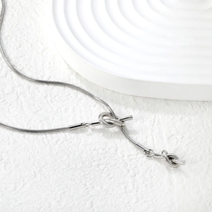 Detailed view of silver snake chain necklace featuring modern abstract knotted metal accents
