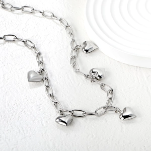 Polished stainless steel heart pendant necklace with thick oval link chain on stone surface