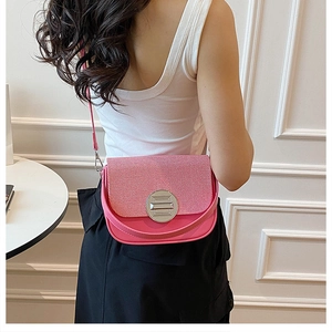 Detail view of pink patchwork crossbody box bag with round silver metal buckle on model