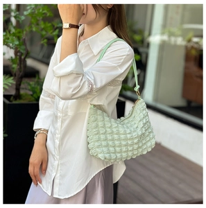 Detailed view of mint green bubble textured fabric on a French style pleated shoulder bag