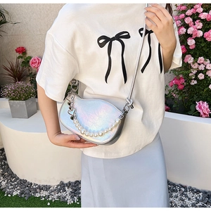 Détail d'un sac demi-lune holographique avec chaîne de perles et pendentif cœur