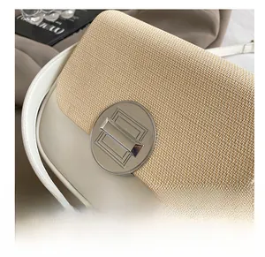 Detailed shot of leather crossbody bag featuring beige woven texture and round silver buckle