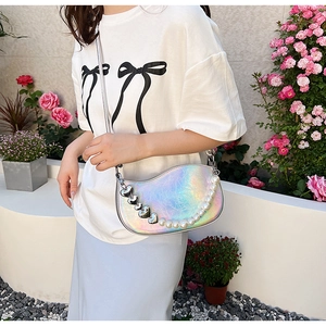 Iridescent silver half-moon bag with pearl and heart chain detail on a model