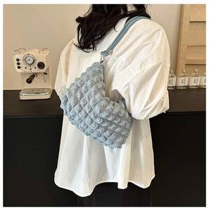 Detailed view of light blue pleated bubble texture fabric shoulder bag worn by model