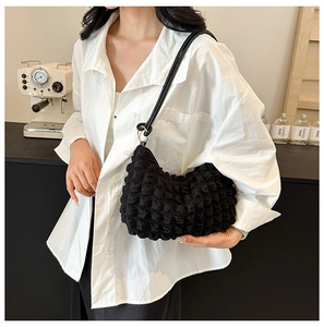 Close-up of black bubble waffle texture hobo bag worn by model in a modern cafe setting