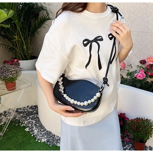 Détail d'un sac demi-lune plissé noir avec chaîne de perles et breloque coeur