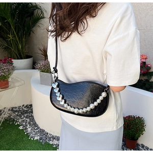 Détail du sac demi-lune noir plissé avec breloques cœur et chaîne de perles