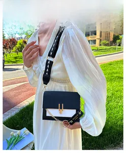 Detail of a black and white PU leather crossbody bag with gold buckle and jacquard strap