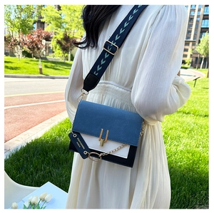 Detail of color-block crossbody bag featuring blue suede flap and gold metal lock