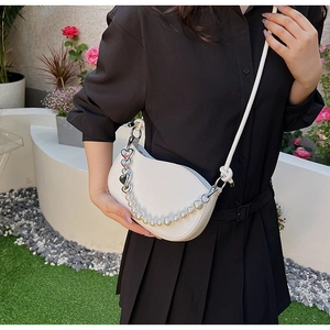 Détail du sac demi-lune blanc avec chaîne décorative en perles et cœurs en argent