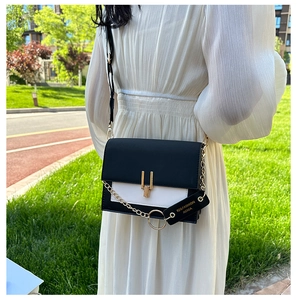 Detail of crossbody bag with black and white contrast design and golden U-shaped buckle