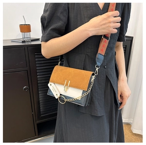 Detailed close-up of a tricolor crossbody bag with woven wide strap and gold chain