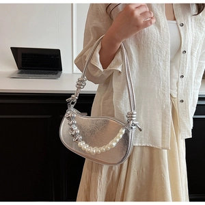 Détail du sac croissant argenté avec simili cuir plissé, chaîne de perles et charms cœur