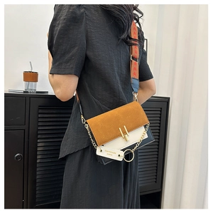 Detail of color-block crossbody bag with wide pattern strap and metallic buckle