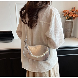 Détail du sac bandoulière argenté avec chaîne décorative en perles et cœurs en métal
