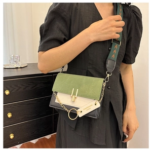 Detail of color-block flap crossbody bag with wide patterned strap and metal hardware