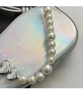 Détail du sac à selle holographique avec chaîne de perles et détails de cœurs argentés