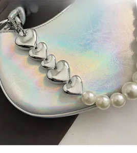 Détail du sac selle holographique argent avec chaîne cœur et bandoulière en perles