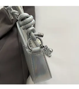 Détail du sac selle argenté avec bandoulière en corde torsadée et anneaux métalliques
