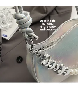 Détail du sac argenté irisé avec fermoir amovible et chaîne en perles et cœurs