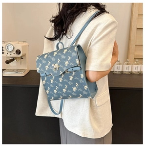 Détail d'un sac à dos bleu avec motif de calèche et logo métallique doré élégant