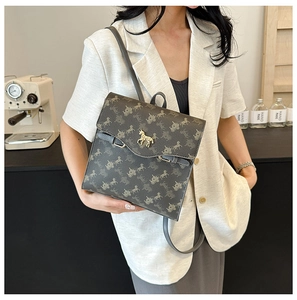 Détail du sac à dos gris avec motif équestre et boucle dorée porté par un mannequin